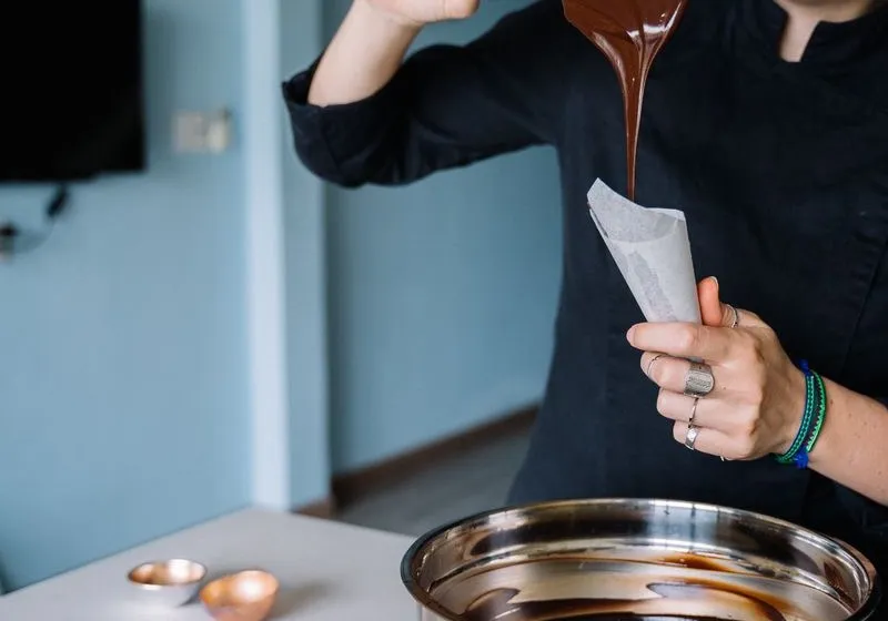 Bonbon- és cukorkakészítő — kézműves cukrász temperált csokoládéval dolgozik